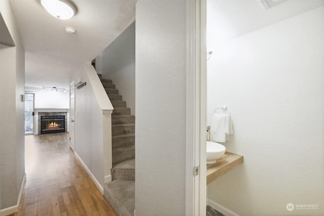 staircase with a tile fireplace and hardwood / wood-style flooring