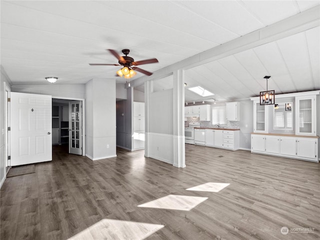 unfurnished living room with hardwood / wood-style floors, vaulted ceiling with beams, and ceiling fan with notable chandelier