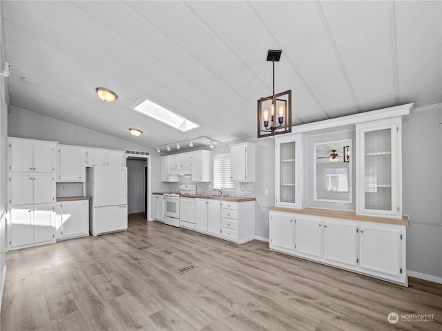 kitchen with lofted ceiling with skylight, light hardwood / wood-style floors, decorative light fixtures, white appliances, and white cabinets