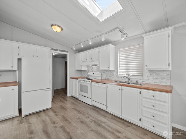 kitchen with white appliances, white cabinets, sink, vaulted ceiling with skylight, and butcher block counters