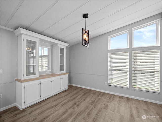 unfurnished dining area with a chandelier, light hardwood / wood-style floors, and a healthy amount of sunlight