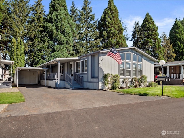 manufactured / mobile home featuring a carport, covered porch, and a front yard