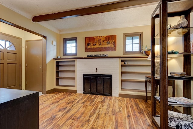 foyer featuring a fireplace, wood-type flooring, a textured ceiling, and beam ceiling