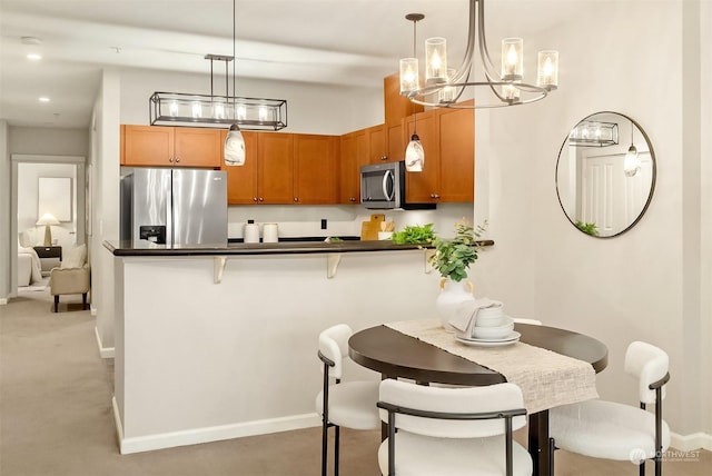 kitchen featuring kitchen peninsula, decorative light fixtures, stainless steel appliances, and a breakfast bar area