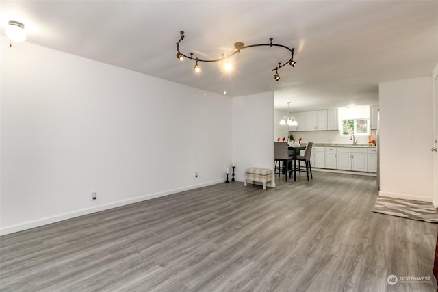 unfurnished living room with hardwood / wood-style floors, track lighting, and sink