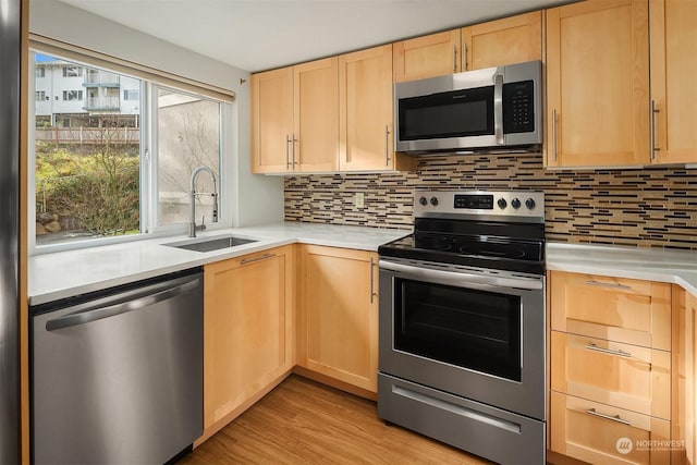 kitchen with stainless steel appliances, plenty of natural light, sink, and light brown cabinetry