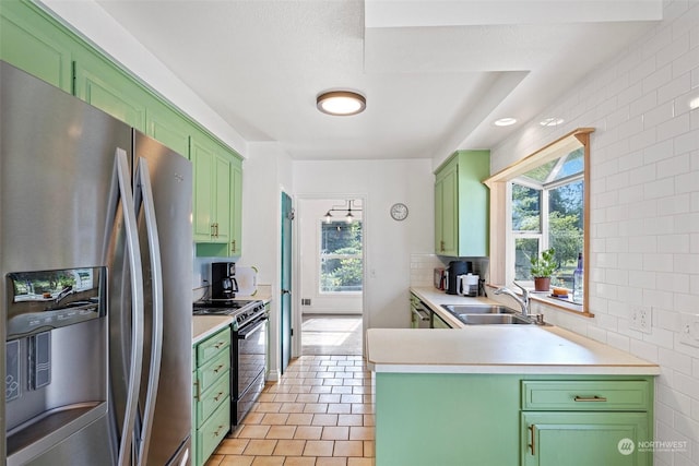 kitchen with appliances with stainless steel finishes, tasteful backsplash, sink, light tile patterned floors, and green cabinetry