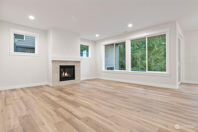 unfurnished living room featuring light hardwood / wood-style floors and a tiled fireplace