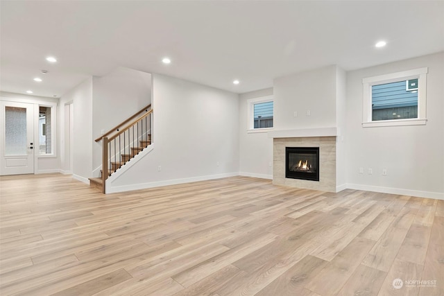 unfurnished living room with baseboards, stairway, light wood-style flooring, and recessed lighting