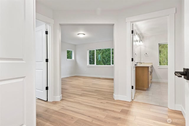 interior space with light wood-style floors, baseboards, and a sink