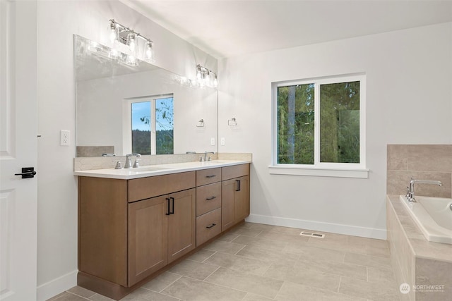 bathroom with tile patterned flooring, vanity, and a relaxing tiled tub