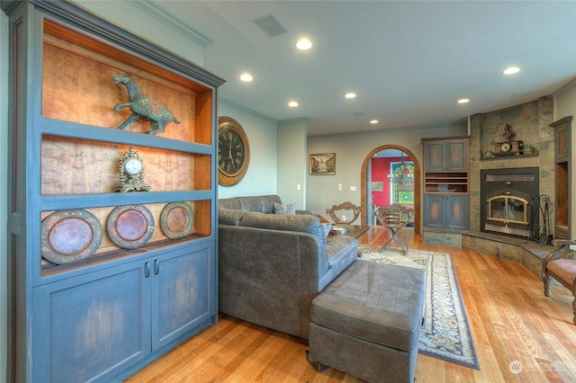 living room featuring a fireplace, light hardwood / wood-style flooring, and ornamental molding