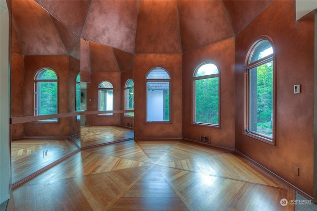 empty room with a wealth of natural light and light parquet flooring