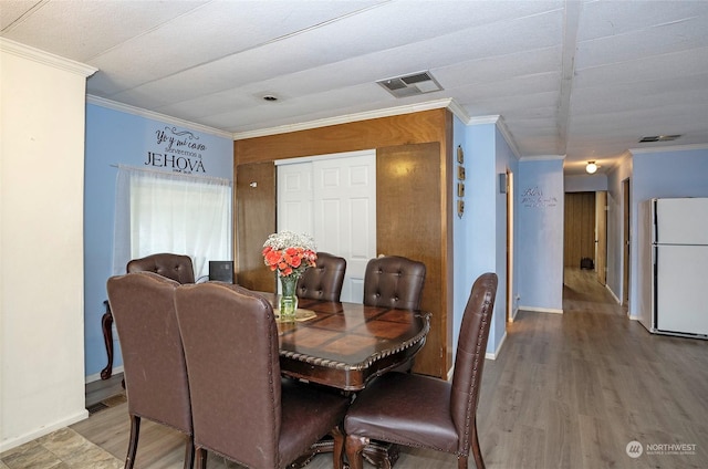 dining area featuring wood-type flooring and ornamental molding