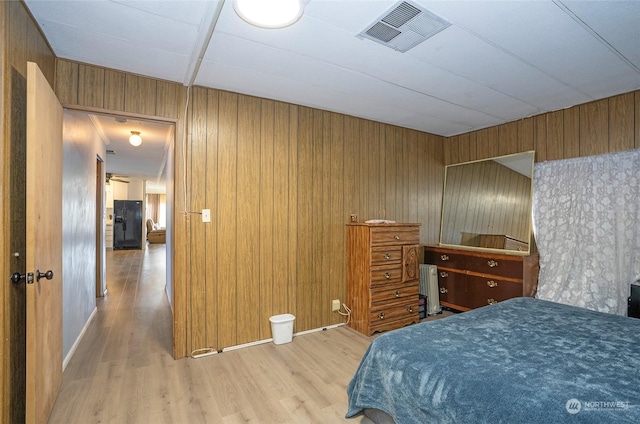 bedroom with wood walls and light hardwood / wood-style flooring