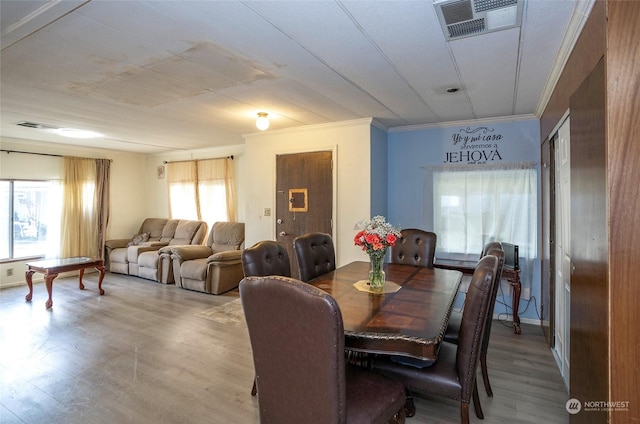 dining area with crown molding, plenty of natural light, and hardwood / wood-style flooring