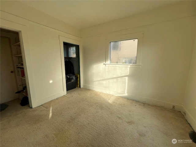 unfurnished bedroom with light colored carpet, a spacious closet, and a closet