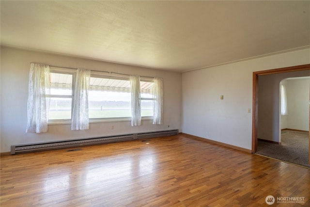 unfurnished room with a baseboard radiator, arched walkways, baseboards, and wood finished floors