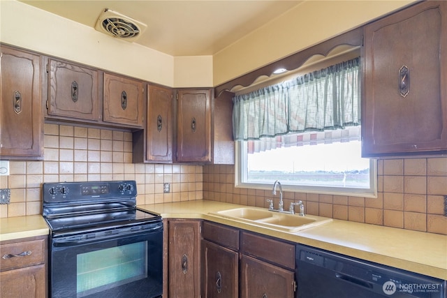 kitchen featuring a sink, tasteful backsplash, visible vents, light countertops, and black appliances