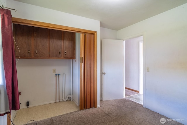 laundry area featuring light colored carpet and cabinet space