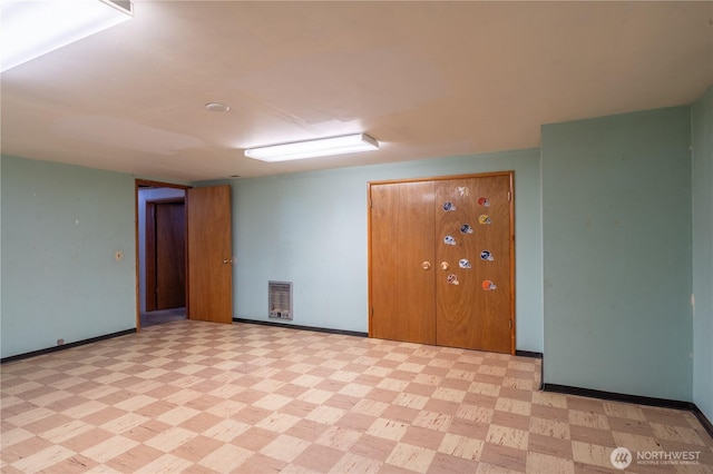 unfurnished room featuring light floors, baseboards, and heating unit