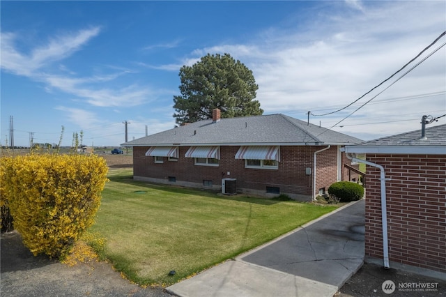 view of home's exterior featuring brick siding, a lawn, central AC, and roof with shingles