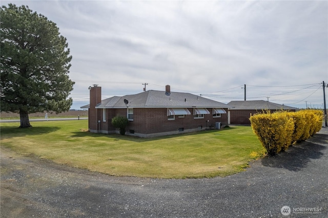 view of home's exterior featuring brick siding, a chimney, a yard, cooling unit, and roof with shingles