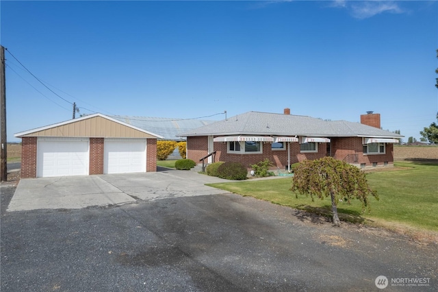 ranch-style house featuring brick siding, an outbuilding, a detached garage, and a front yard