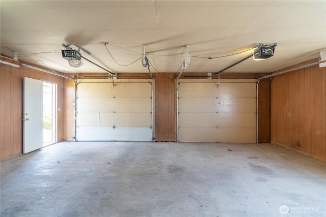 garage with a garage door opener and wooden walls