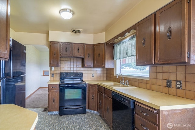 kitchen with black appliances, decorative backsplash, a sink, and light countertops