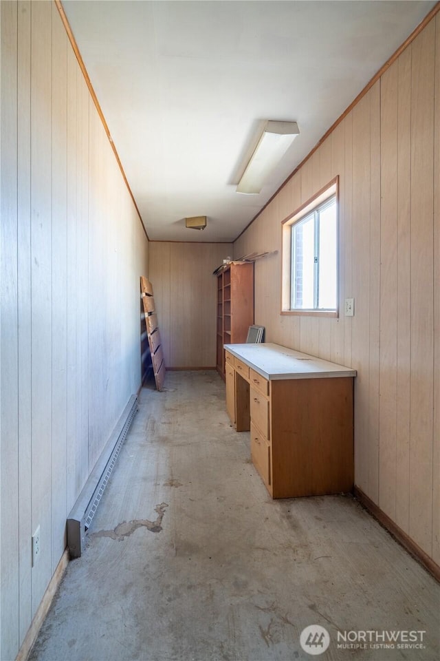 interior space with a baseboard heating unit, light carpet, and wood walls