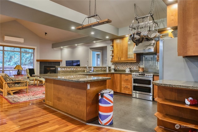 kitchen featuring sink, a wall mounted air conditioner, tasteful backsplash, wood-type flooring, and range with two ovens