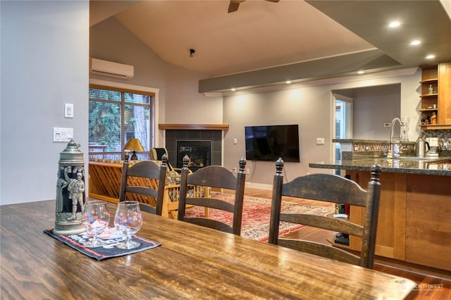 dining area with dark hardwood / wood-style flooring, an AC wall unit, bar area, lofted ceiling, and a fireplace