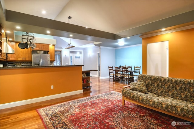 living room featuring lofted ceiling, light hardwood / wood-style flooring, and ornamental molding