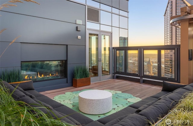 exterior space featuring french doors, a glass covered fireplace, and visible vents