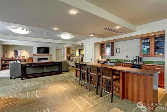 bar featuring visible vents, a fireplace, a sink, indoor wet bar, and light colored carpet