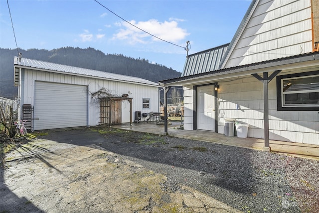 view of side of property with a mountain view, a garage, and an outbuilding