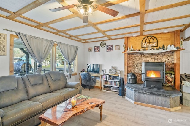 living room with beamed ceiling, ceiling fan, light wood-type flooring, and a wood stove