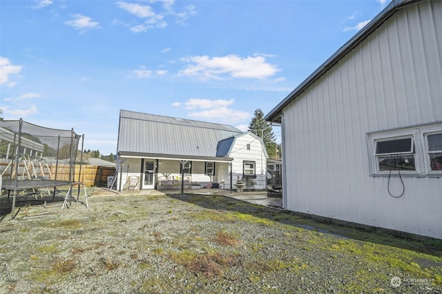 back of property featuring a patio area, a trampoline, and a yard