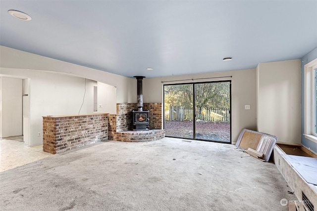 unfurnished living room with a wood stove and light colored carpet