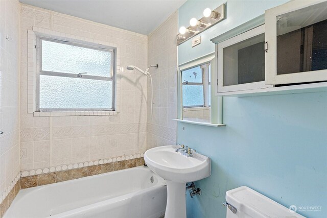 bathroom with plenty of natural light, tiled shower / bath combo, and toilet