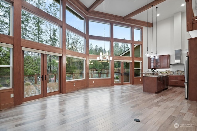 interior space featuring beam ceiling, french doors, and a high ceiling