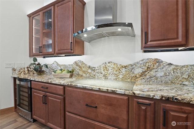 kitchen featuring beverage cooler, hardwood / wood-style flooring, black electric stovetop, light stone counters, and wall chimney range hood