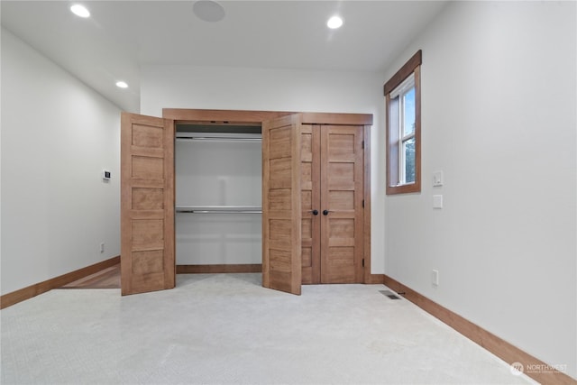 unfurnished bedroom featuring light colored carpet and a closet