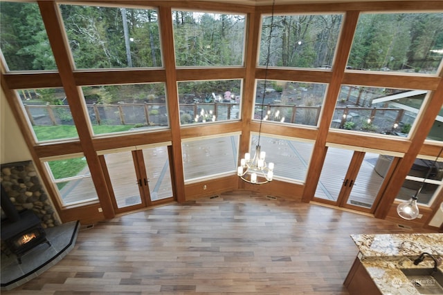 unfurnished sunroom featuring an inviting chandelier, french doors, and a wood stove