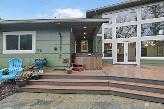 view of exterior entry with a hot tub, a wooden deck, and french doors