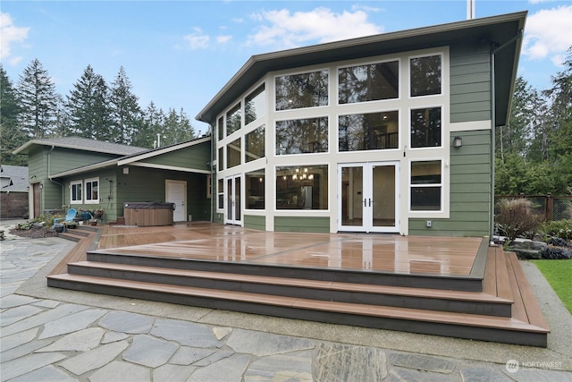 rear view of house featuring french doors, a hot tub, a wooden deck, and a patio