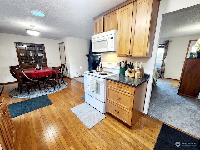 kitchen with a textured ceiling, white appliances, and light hardwood / wood-style floors