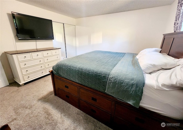 carpeted bedroom with a closet and a textured ceiling