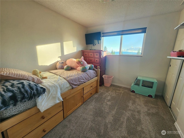 bedroom with a textured ceiling and dark carpet